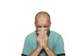 Young bald man sick from common cold flu blowing his nose with paper tissue isolated on white background. Royalty Free Stock Photo