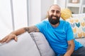 Young bald man smiling confident sitting on sofa at home Royalty Free Stock Photo