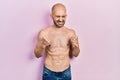 Young bald man standing shirtless excited for success with arms raised and eyes closed celebrating victory smiling Royalty Free Stock Photo