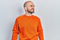 Young bald man wearing casual clothes looking to side, relax profile pose with natural face and confident smile Royalty Free Stock Photo