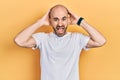 Young bald man wearing casual white t shirt crazy and scared with hands on head, afraid and surprised of shock with open mouth Royalty Free Stock Photo