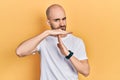 Young bald man wearing casual white t shirt doing time out gesture with hands, frustrated and serious face Royalty Free Stock Photo