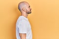 Young bald man wearing casual white t shirt looking to side, relax profile pose with natural face and confident smile Royalty Free Stock Photo