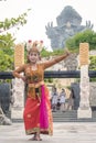 A Young Balinese Woman Dancing with the Garuda Wisnu Kencana Statue in the Background Royalty Free Stock Photo