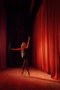 Young ballerina in black clothe on stage with red curtains