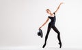 Young ballerina in black pointe shoes and black bondage costume posing on white background with hat in hand Royalty Free Stock Photo