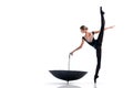 A young ballerina in black pointe shoes and leotard posing with umbrella in graceful pose isolated on white background