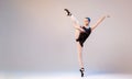 Young ballerina in a black swimsuit and pointes dances against bright background Royalty Free Stock Photo