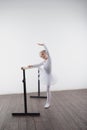 Young ballerina girl in a white tutu. Adorable child dancing classical ballet in a white studio with wooden floor. Children dance. Royalty Free Stock Photo