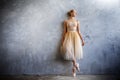 Young ballerina in a golden colored dancing costume is posing in a loft studio