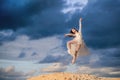 Young ballerina in a light long white dress flies in a jump