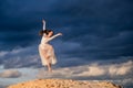 Young ballerina in a light long white dress flies in a jump