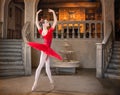 Young ballerina in a red tutu is dancing against background of the theatrical scenery of the palace Royalty Free Stock Photo