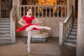 Young ballerina in a red tutu is dancing against background of the theatrical scenery of the palace Royalty Free Stock Photo