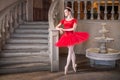 Young ballerina in a red tutu is dancing against background of the theatrical scenery of the palace Royalty Free Stock Photo