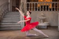 Young ballerina in a red tutu is dancing against background of the theatrical scenery of the palace Royalty Free Stock Photo