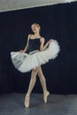 young ballerina in a tutu and pointe shoes standing against the wall posing ballet elements