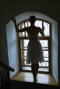 Young ballerina in white dress and satin ballet shoes posing on a old window in a dark room Royalty Free Stock Photo
