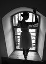 Young ballerina in white dress and satin ballet shoes posing on a old window in a dark room. black and white Royalty Free Stock Photo