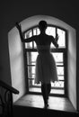 Young ballerina in white dress and satin ballet shoes posing on a old window in a dark room. black and white Royalty Free Stock Photo