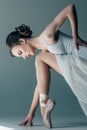 young ballerina in white dress stretching