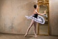 Young ballerina in a white tutu poses near beautiful old mummer in vintage interior, reflecting many times Royalty Free Stock Photo