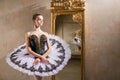 Young ballerina in a white tutu poses near beautiful old mummer in vintage interior, reflecting many times Royalty Free Stock Photo