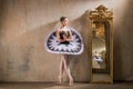 Young ballerina in a white tutu poses near beautiful old mummer in vintage interior, reflecting many times Royalty Free Stock Photo