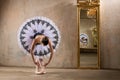 Young ballerina in a white tutu poses near beautiful old mummer in vintage interior, reflecting many times Royalty Free Stock Photo