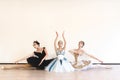 Young ballerinas perform paired exercises against a white background in the studio