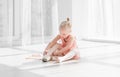 Young ballet dancer in tutu sitting on the floor and tying pointe shoes Royalty Free Stock Photo