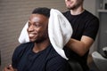 Young barber dries clients hair with soft towel