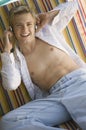 Young bare-chested man on deckchair listening to music on headphones portrait Royalty Free Stock Photo