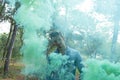 Young bare man in colored smoke outdoors in the forest