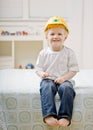 Young barefoot boy sitting on bed in bedroom