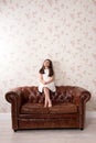 Young girl sitting on a leather couch Royalty Free Stock Photo