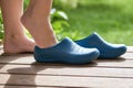 Young Barefoot gurl puts rubber boots on standing on the porch of a country house