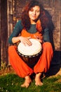 Young barefoot lady drummer playing on her djembe drum on rustic wooden door background Royalty Free Stock Photo