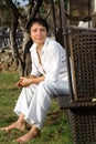 Young barefoot woman dressed white sits on bench