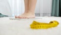 Young barefoot woman walking in bedroom and standing on scales. Concept of dieting, loosing weight and healthy lifestyle