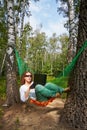 Young barefooted woman in dark sunglasses lies in hammock