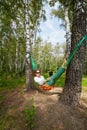 Young barefooted woman in dark sunglasses lies in hammock