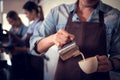 Young barista adept in champion coffee brewing, creating latte art in a cup of coffee