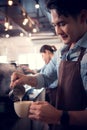 Young barista adept in champion coffee brewing, creating latte art in a cup of coffee