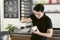 Young barista male work in a coffee shop and making coffee. Barista making cappuccino, bartender preparing coffee drink. Portrait Royalty Free Stock Photo