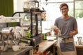 Young barista standing in his coffee house