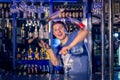 Young barman juggles bottles. Flaring.