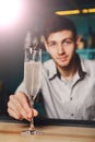 Young Barman offers champagne glass in night club bar