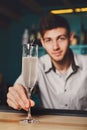 Young Barman offers champagne glass in night club bar