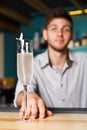 Young Barman offers champagne glass in night club bar